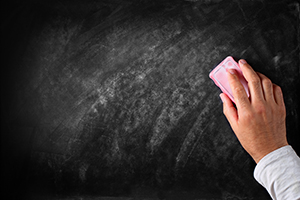 A hand erasing the writings on the chalkboard